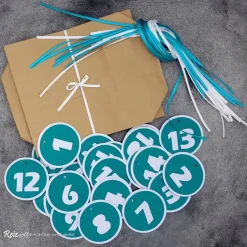 Adventskalender|Reizvolle Karten und mehr Adventskalender Papierbeutel zum Befüllen mit türkis-weißen Zahlenanhängern & Satinbändern